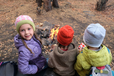 Kids sitting near fire pit in forest
