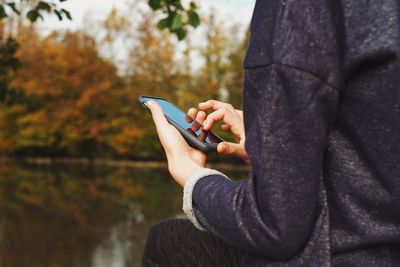 Cropped image of woman using smart phone at park