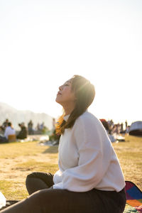 Side view of a young woman sitting on land