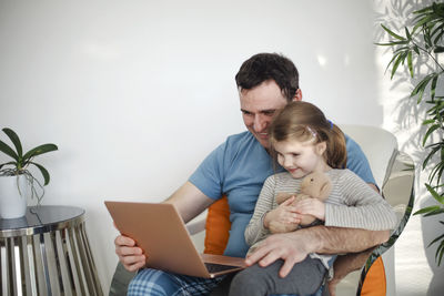 Smiling father and daughter looking at laptop