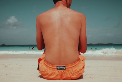 Rear view of shirtless man standing on beach