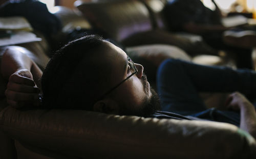 High angle view of thoughtful man relaxing on sofa at home