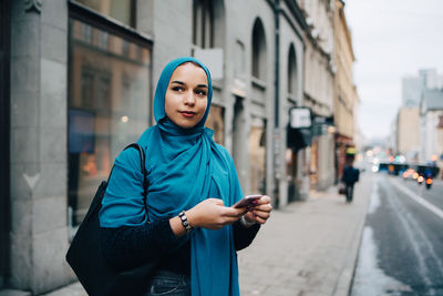 Full length of young woman standing on city street