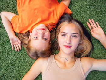  happy teenage sisters lie on the grass and smile in the park