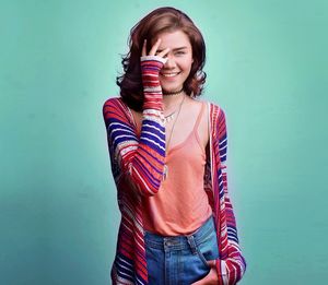 Portrait of young woman standing against blue background