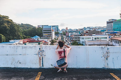 Rear view of woman with umbrella against buildings in city