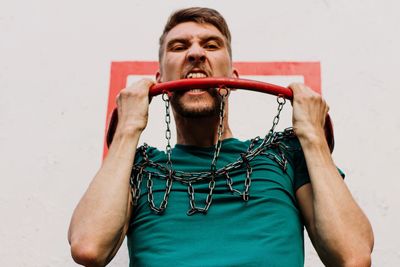 Portrait of man holding camera against wall