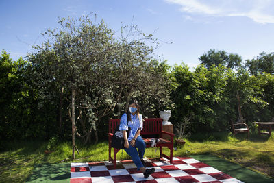 People sitting on seat against trees