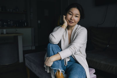 Portrait of smiling woman sitting in living room at home