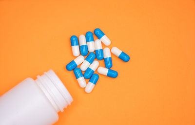 Directly above shot of capsules and bottle over orange background