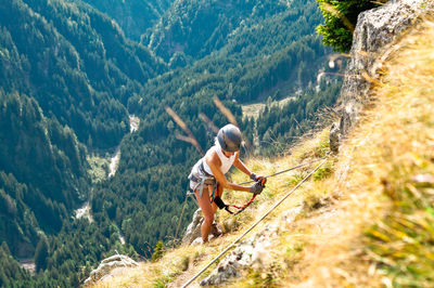 Full length of woman climbing rocks in a mountain at heini-holzer-klettersteig