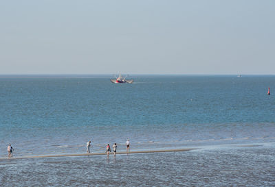 People on beach against clear sky