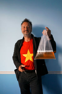 Portrait of man holding plastic bag filled with beer