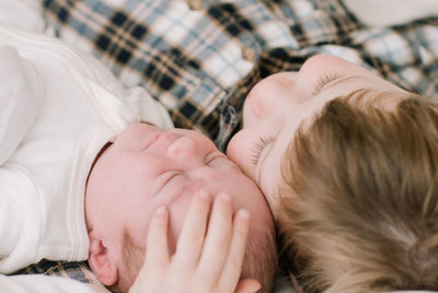 Big brother and newborn baby sister snuggling on bed