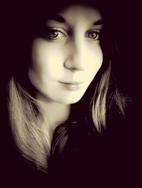 Close-up portrait of young woman against black background