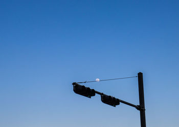 Low angle view of poles hanging against clear blue sky