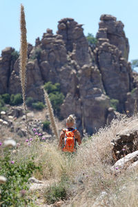 Woman hiking in canyon and disappearing against desert, rock formations, and sky