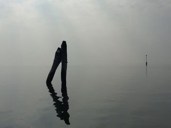 Silhouette person standing by sea against sky