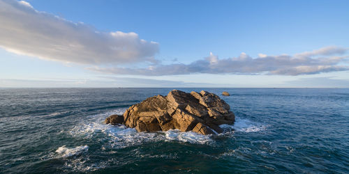 Rock formation in sea against sky