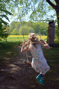 Rear view of girl enjoying on swing at park