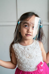 Cute girl wearing face shield at home