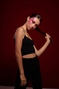 Side view of young woman exercising against wall