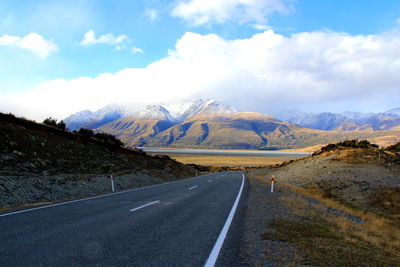 Scenic view of road by mountains against sky