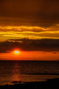 Scenic view of sea against dramatic sky during sunset