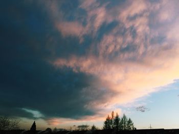 Low angle view of silhouette trees against dramatic sky