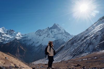 Rear view of woman walking on snowcapped mountains against sky