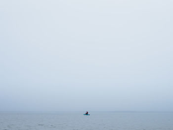 Man sailing on sea against clear sky