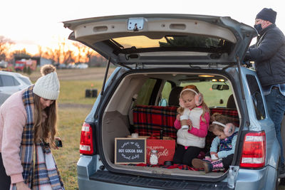 Cute family gathered by car outdoors