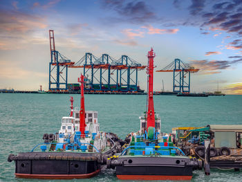 Cranes at commercial dock against sky