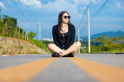 Woman sitting on road against the sky