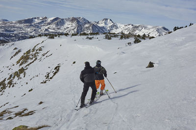 Rear view of people skiing on snowcapped mountain