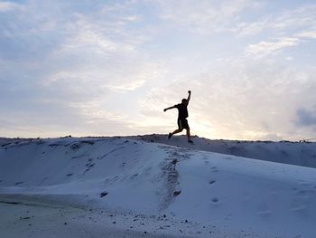 Silhouette man on snow covered land against sky