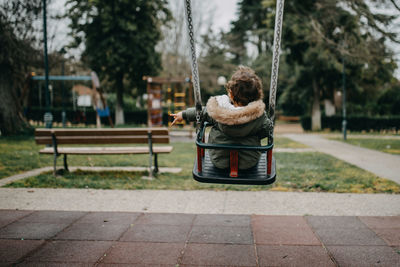 Rear view of woman holding umbrella in park