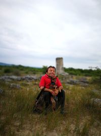 Portrait of man sitting on field with dog