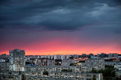 Cityscape against dramatic sky during sunset