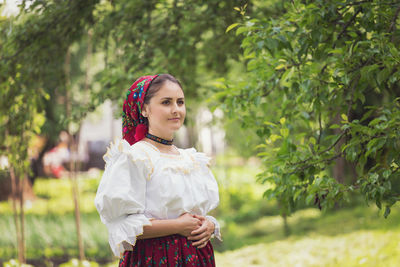 Portrait of young woman standing against plants