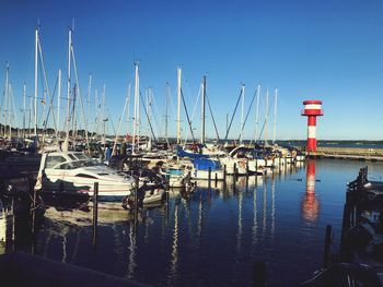 Sailboats moored at harbor against clear blue sky