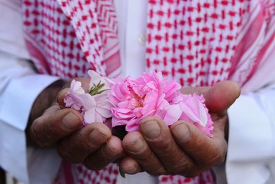 Midsection of man holding pink roses