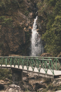 Footbridge against waterfall in forest
