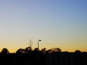 Silhouette street lights against clear sky during sunset