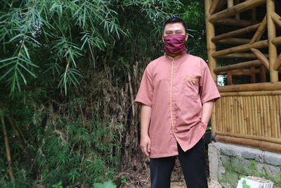 Full length of young man standing against pink plants