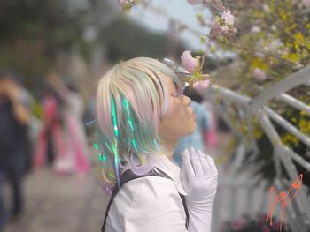 Portrait of woman with pink flowers against trees