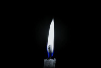 Close-up of lit candle in darkroom