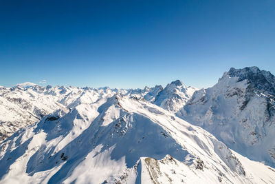 Scenic view of snowcapped mountains against clear blue sky