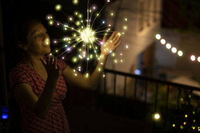 Midsection of woman holding illuminated light painting at night