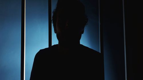 Portrait of silhouette man standing against window